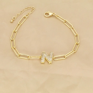 Detailed view of an 18k gold-plated paperclip chain bracelet with a cubic zirconia N pendant