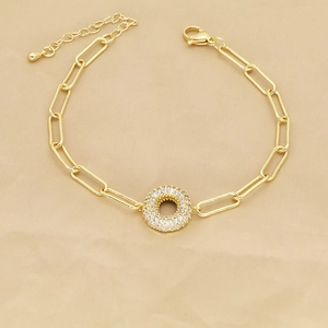 Detailed view of golden paperclip chain bracelet with zircon-encrusted round charm