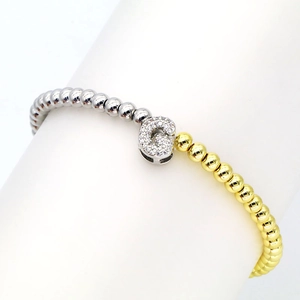 Detail of 18k gold and silver beaded bracelet featuring a pavé zircon letter G charm