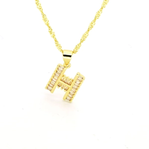 Macro d'un pendentif lettre H plaqué or avec pierres en zircon et fine chaîne torsadée