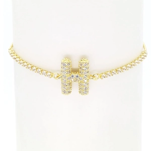 Close-up of 18k gold plated bracelet featuring a cubic zirconia paved letter H on a stand