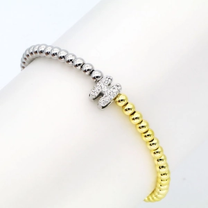 Detail of beaded bracelet showing mixed gold and silver beads with a micro-pave letter H charm