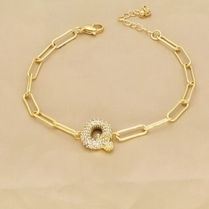 Detailed view of the 18k gold paperclip chain bracelet with a sparkling zircon letter Q charm