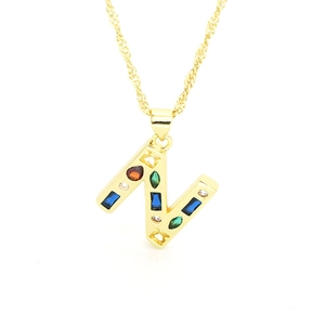 Detail shot of golden letter N pendant with colorful zircon stones on water wave chain