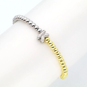 Macro detail of 18k gold plated beaded bracelet with cubic zirconia letter K charm