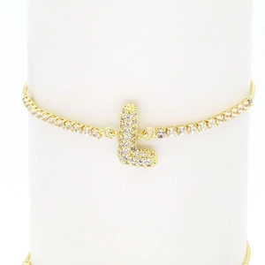 Macro view of 18k gold letter L bracelet with sparkling cubic zirconia on white pillar