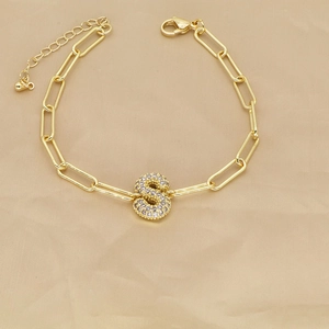 Detailed close-up of 18k gold paperclip chain bracelet with a cubic zirconia letter S charm