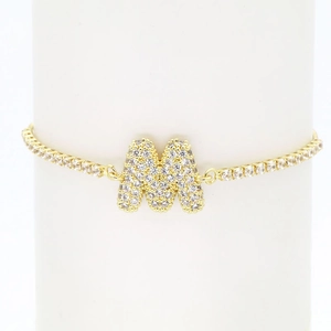 Detailed macro view of 18k gold plated tennis chain bracelet with crystal letter M pendant