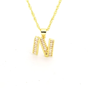 Détail macro du collier pendentif lettre N doré avec zircons rectangulaires sertis sur blanc