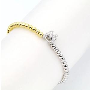 Macro detail of 18k gold and silver two-tone beaded bracelet with zircon paved M letter