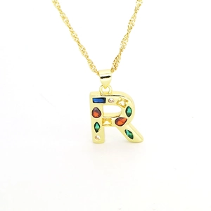 Macro shot of gold-plated letter R pendant with colorful cubic zirconia and water wave chain