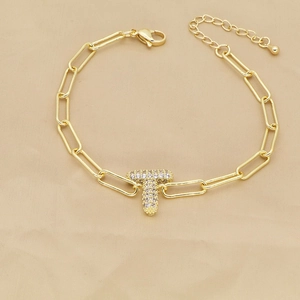 Detail of 18k gold plated paperclip chain bracelet featuring a zircon letter T charm