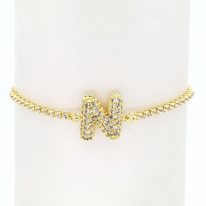 Detailed macro view of 18k gold tennis chain featuring a pavé zircon capital letter N charm