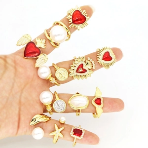 Detailed shot of vintage gold rings featuring red hearts and faux pearls on hand