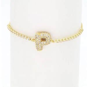 Macro shot of gold tennis bracelet with a crystal-encrusted letter P charm on a display