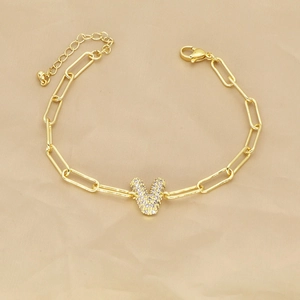 Detailed macro view of 18k gold paperclip chain bracelet with zircon pavé letter V pendant