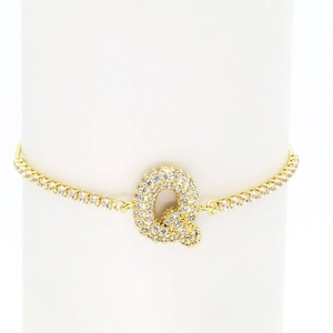 Close-up of gold plated tennis bracelet with sparkling zircon letter Q pendant charm