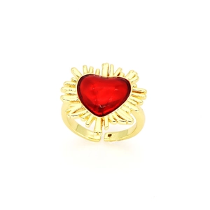 Detail of vintage gold ring featuring a large red heart stone with golden sunburst rays
