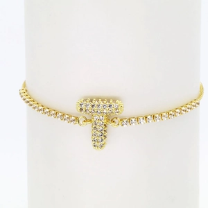 Close-up of golden 18k tennis bracelet with sparkling zircon letter T pendant