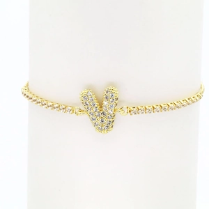 Detailed close-up of 18k gold V-letter pendant with zircon inlay on a tennis bracelet