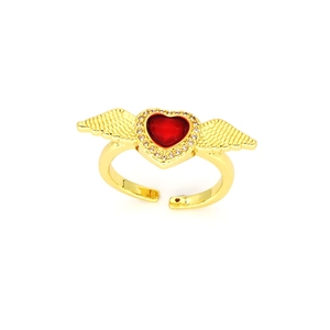 Macro detail of gothic gold ring with red heart and sparkling angel wing accents