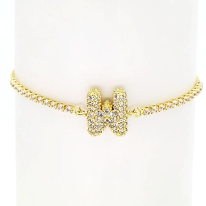 Detail of 18k gold tennis bracelet featuring a sparkling zircon pavé bubble letter W charm