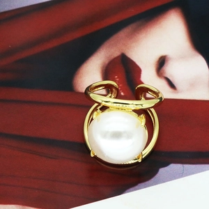 Detail of a minimalist gold ring with a large white pearl on a fashion magazine background