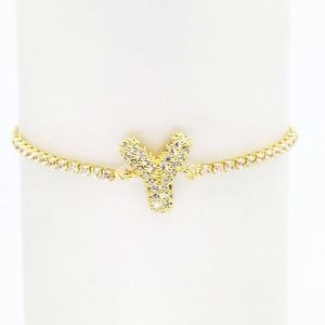 Detailed close-up of 18k gold tennis bracelet with iced-out Y letter balloon pendant