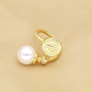 Detail of vintage gold ring with St. Benedict medal, large white pearl and micro-pave crystals