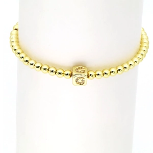 Detail eines 18k vergoldeten Perlenarmbands mit einem G-Anhänger und Zirkoniasteinen