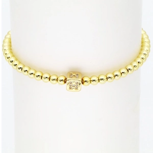 Makro-Detail des 18k Gold-Perlenarmbands mit Kristall-besetztem Buchstaben-H-Anhänger