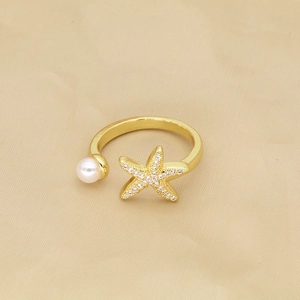 Detail of gold starfish ring with pavé zircons and a white pearl on silk fabric