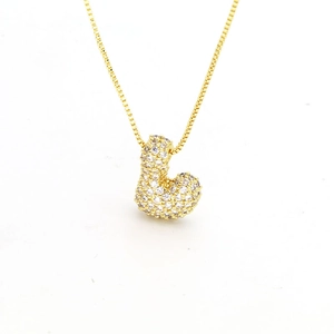 Detailed view of a gold-plated bubble letter pendant necklace with pavé zircon crystals