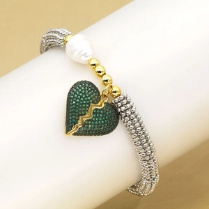 Détail macro du bracelet perlé élastique avec pendentif cœur en zircon vert et perle