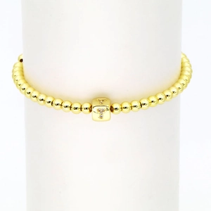 Detail eines 18k Gold Würfelarmbandes mit Kristall-T-Buchstabenanhänger und Goldperlen
