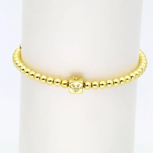 Detailaufnahme eines goldenen Perlenarmbands mit glitzerndem V-Buchstabenwürfel-Anhänger