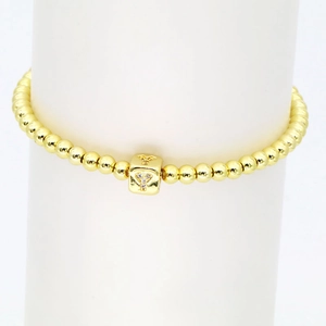 Detail eines 18k vergoldeten Stretch-Armbands mit Goldperlen und quadratischem Y-Anhänger