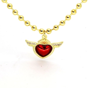 Détail du collier doré avec pendentif cœur rouge ailé et oxydes de zirconium