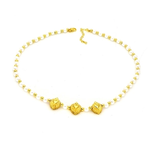 Détail du collier de perles avec billes dorées et trois pendentifs en forme de cœur