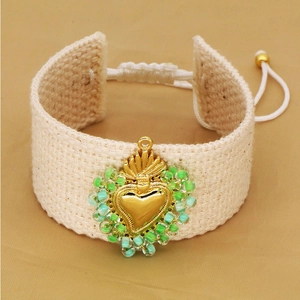 Handmade bohemian woven bracelet featuring a golden sacred heart charm and seed beads