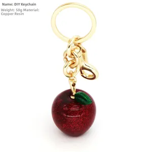 Macro detail of red glitter apple keychain with golden hardware and resin material