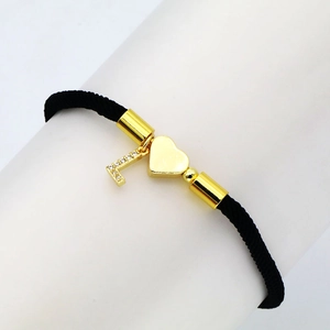 Detailed view of black woven bracelet with golden heart and zircon-inlaid letter L