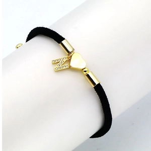 Detail of black woven cord bracelet with gold heart charm and crystal letter N pendant