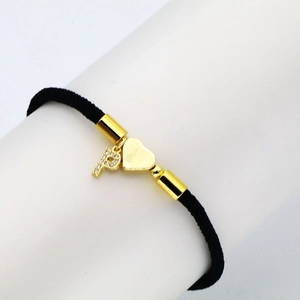 Detail of black woven rope bracelet with gold heart and zircon letter P pendant