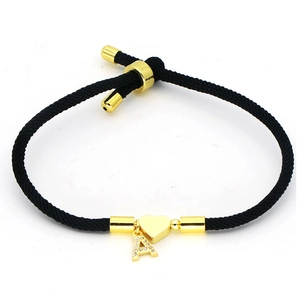 Detail view of adjustable black rope bracelet with golden heart and letter A zircon charm