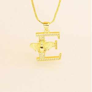 Macro detail of gold letter E necklace featuring a small bee and cubic zirconia stones