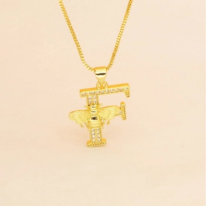 Macro detail of gold letter F pendant with pave zircons and a small honeybee