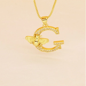 Detailed view of a gold G letter pendant with a bee motif and clear zircon stones