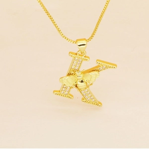 Macro detail of gold letter K pendant with micro-pave diamonds and 3D carved bee