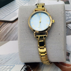 Elegante goldene Quarzuhr mit römischen Ziffern auf einem grauen Samtkissen